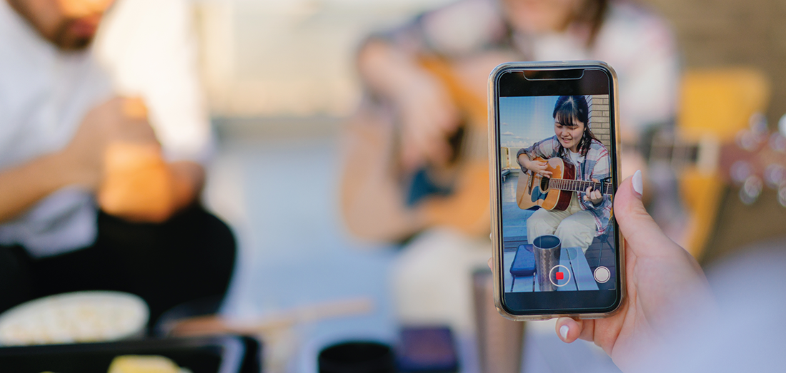 a person filming someone playing guitar on a smartphone.