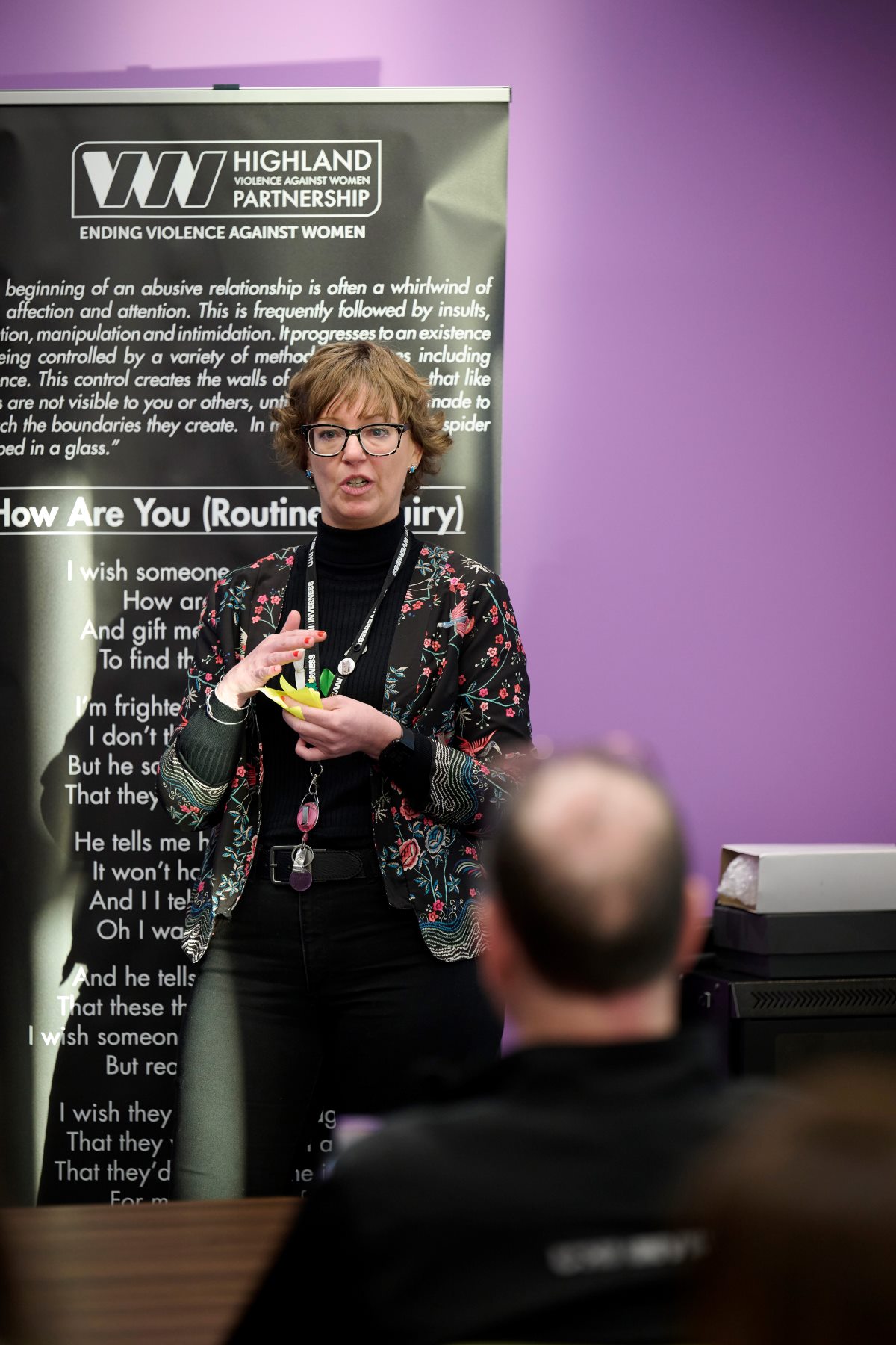 Claire Kilburn-Young standing in a classroom by a tall banner Claire Kilburn-Young standing in a classroom by a tall banner