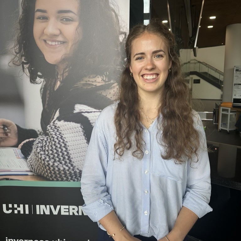 student Amy Mustarde standing by college banner student Amy Mustarde standing by college banner