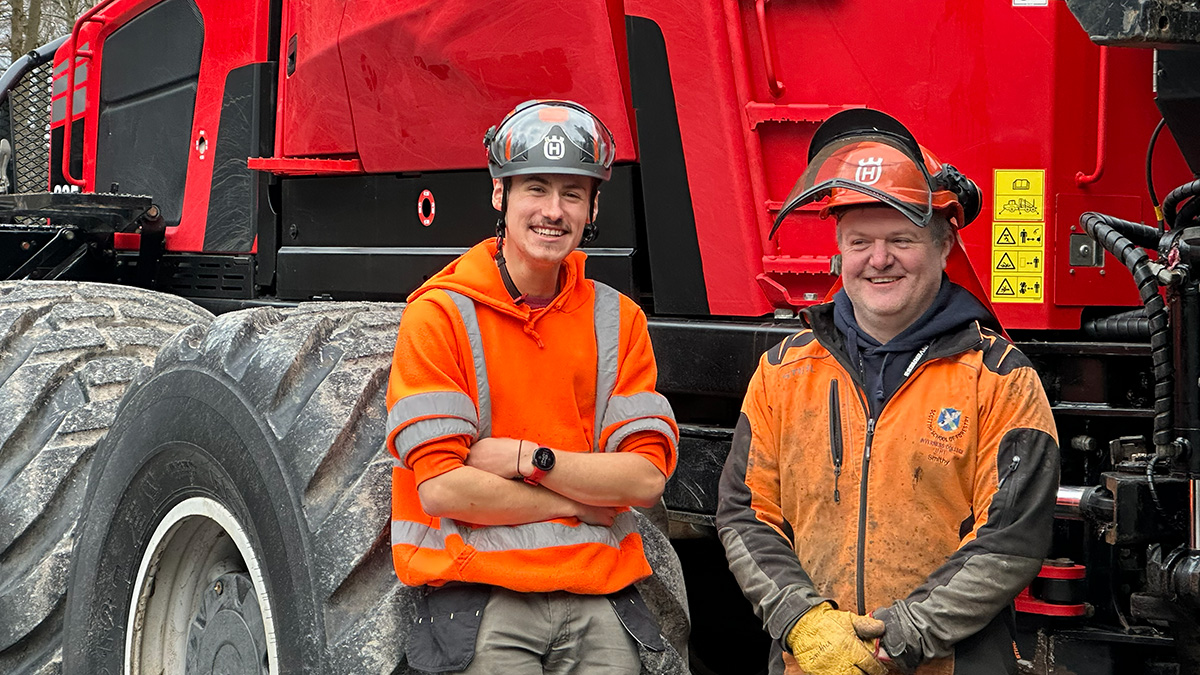 Close up of a student and lecturer in PPE standing by an eight wheeler machine