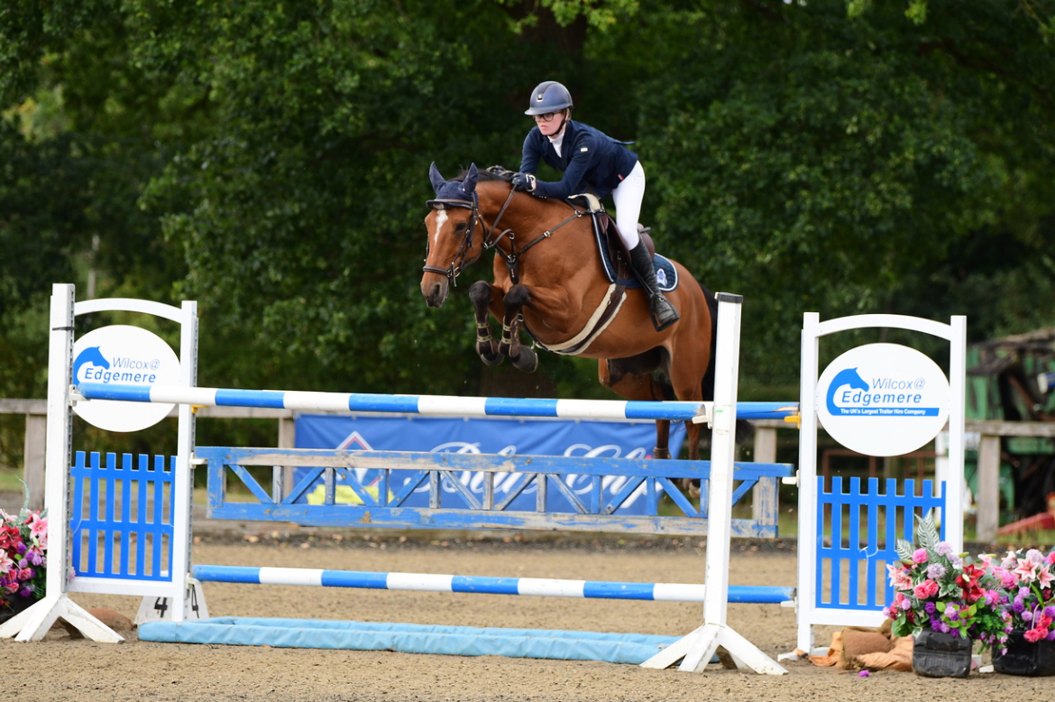 Student show jumping with a horse at a competition