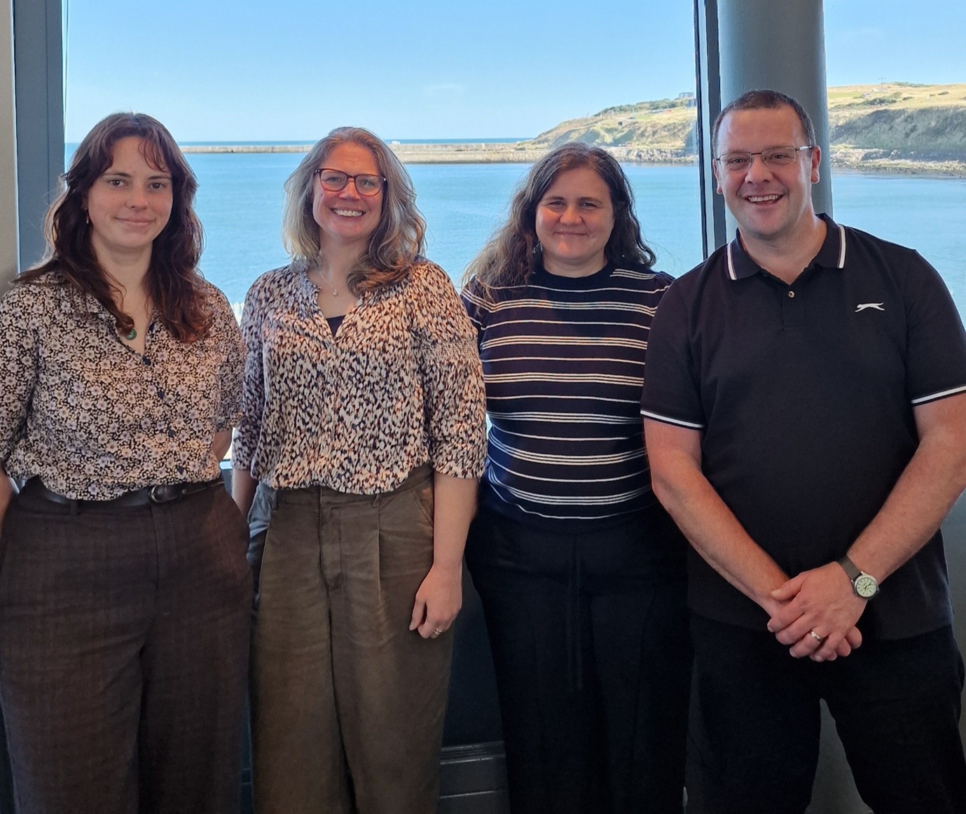 Four people stand in front of a window smiling