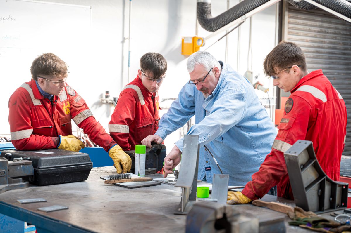 Person demonstrating manufacturing process to three students