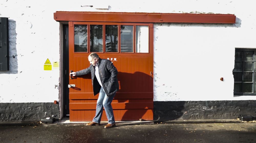 A man pulling open a large red door