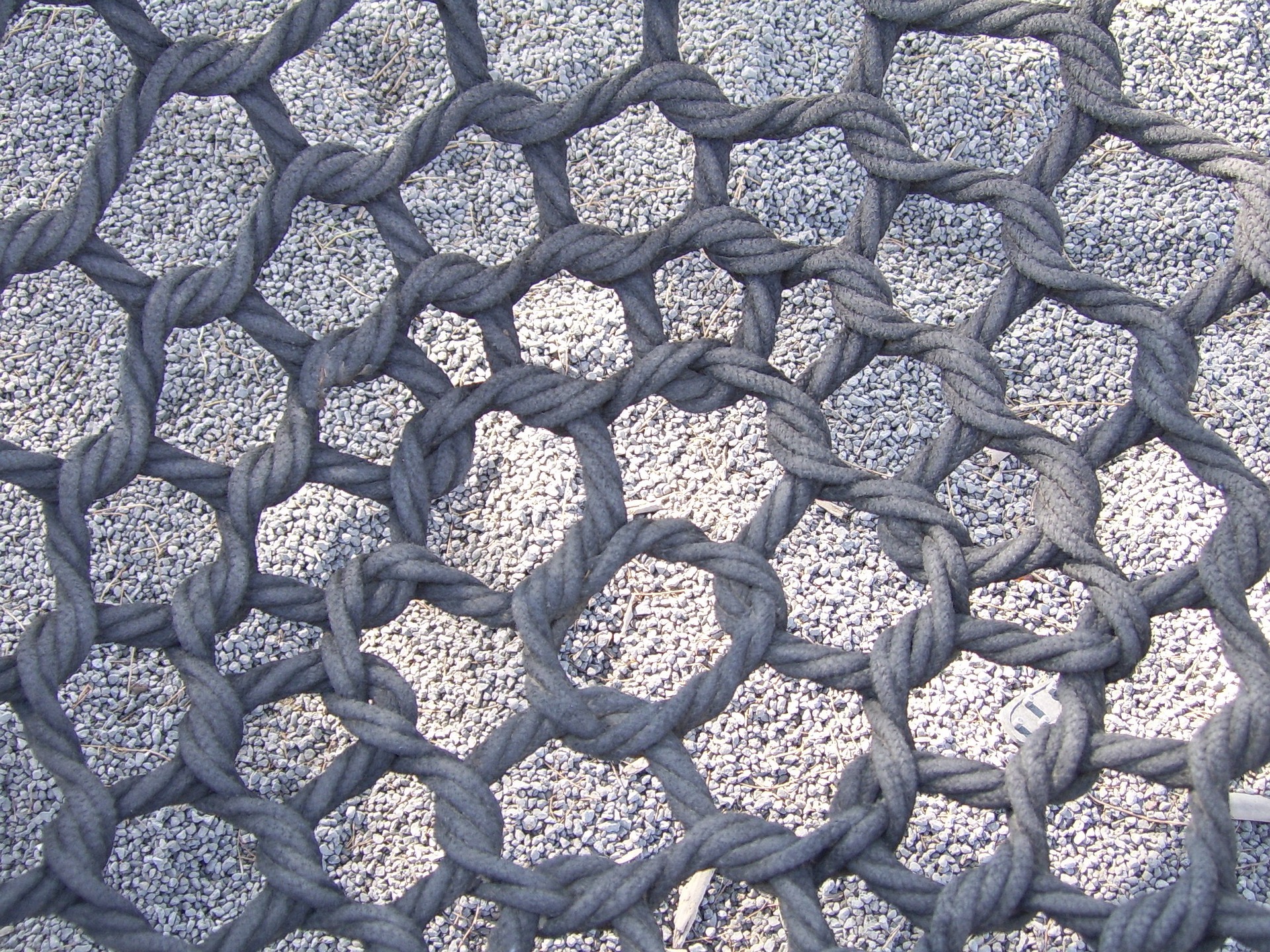 A rope net above some gravel A rope net above some gravel