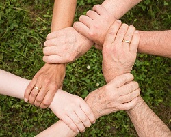 Six people linking hand to wrist in a circle