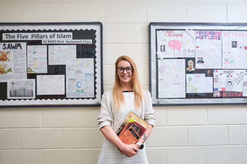 Eva Lovell in a school hallway holding books