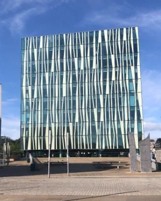 A glass-fronted, cube-shaped building in shades of white and blue, depicted against the blue sky A glass-fronted, cube-shaped building in shades of white and blue, depicted against the blue sky