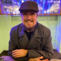Man wearing a flat cap and peacoat smiling at the camera Man wearing a flat cap and peacoat smiling at the camera