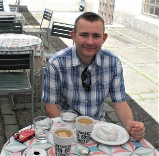 Man sitting at a cafe table in sunshine