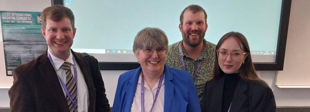 A group of two women and two men facing the camera, all wearing matching conference pack lanyards A group of two women and two men facing the camera, all wearing matching conference pack lanyards