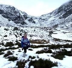 Woman wearing hiking gear, standing in a snowy landscape of hills and grassland. Woman wearing hiking gear, standing in a snowy landscape of hills and grassland.