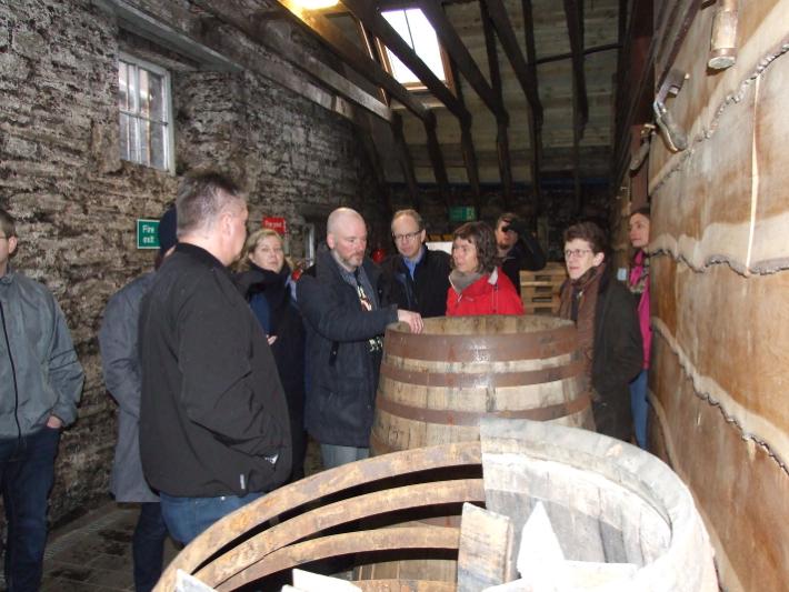 People looking at a wooden barrel