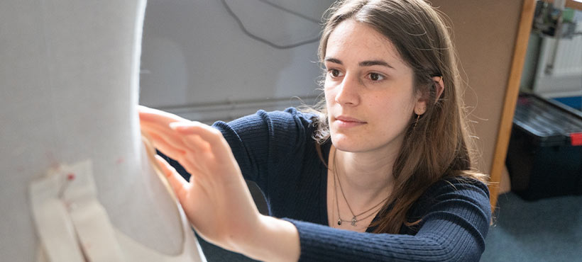 Student Sapho pinning garment pattern pieces to a mannequin Student Sapho pinning garment pattern pieces to a mannequin